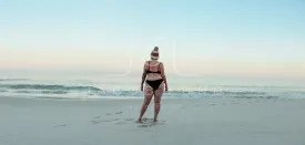 Anonymous female winter bather standing at the beach